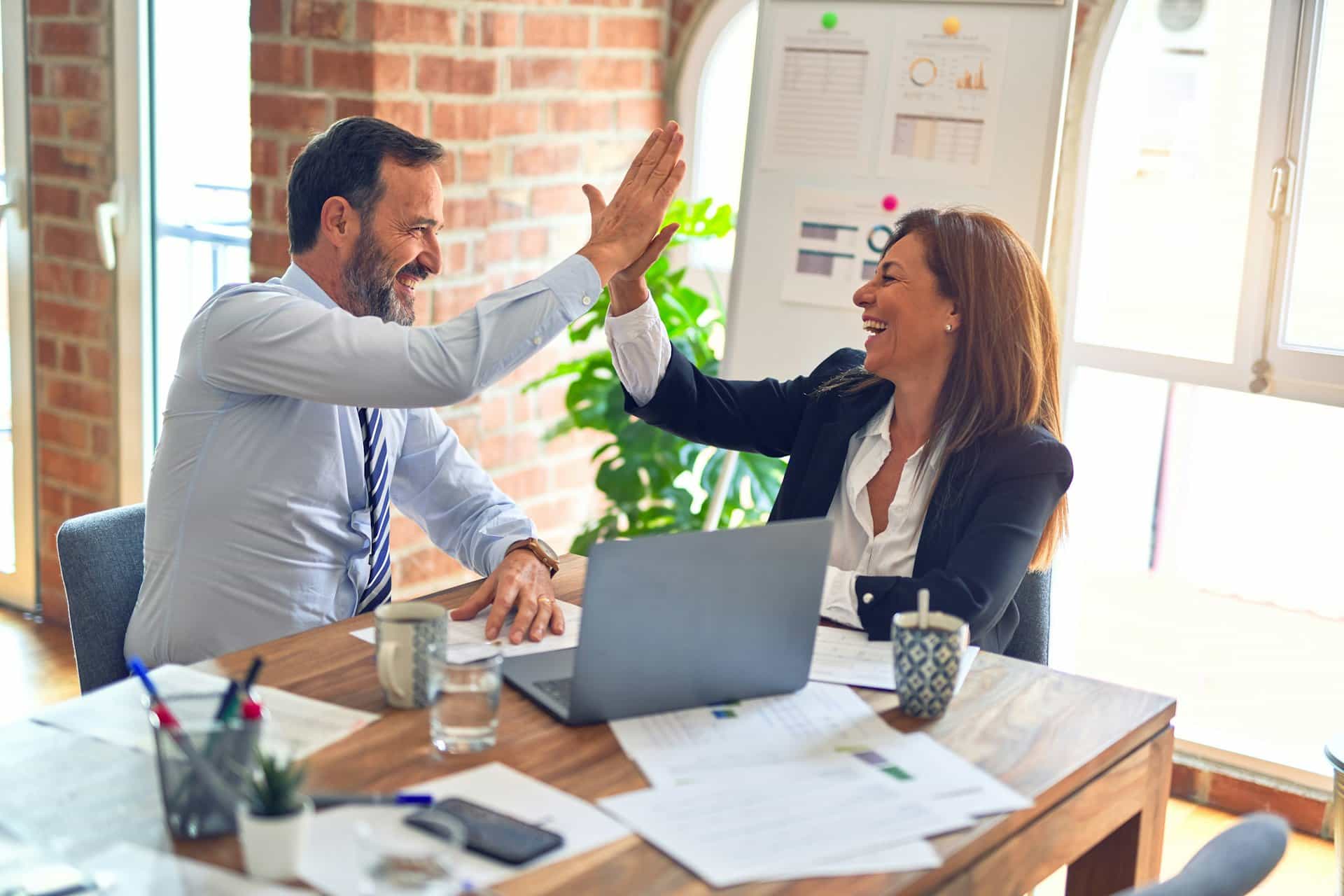 Client and consultant celebrating a successful outcome in an office
