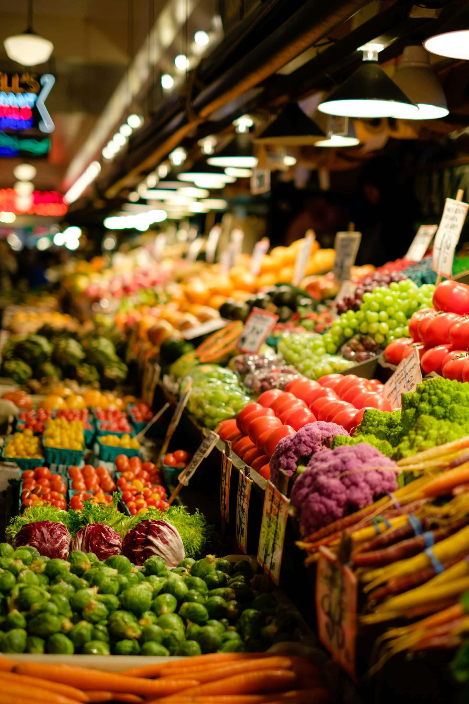 Tomatoes, peppers and greens arranged at a fresh produce market stall